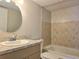 Bathroom with a vanity, sink, and a tiled shower-tub combination with modern fixtures at 14663 Norwood Oaks Dr # 103, Tampa, FL 33613