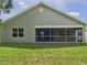 Exterior view of the home features a screened-in patio and green yard at 10169 Holly Berry Dr, Weeki Wachee, FL 34613