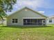 Rear exterior view showing a screened patio and lush green backyard at 10169 Holly Berry Dr, Weeki Wachee, FL 34613