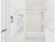 Bright bathroom featuring a shower-tub, white tile flooring, and a window with views of the neighborhood at 10169 Holly Berry Dr, Weeki Wachee, FL 34613