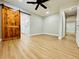 Light-filled bedroom with modern floors, a ceiling fan, and a rustic sliding barn door at 4201 S Renellie Dr, Tampa, FL 33611