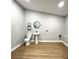 Laundry room featuring modern toilet, wood-look floors, and compact washing/drying hookups at 4201 S Renellie Dr, Tampa, FL 33611