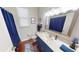 Bathroom with navy vanity, granite counters, large mirror and shower with blue curtain at 4506 Gentrice Dr, Valrico, FL 33596