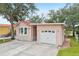 Charming home with a driveway leading to an attached garage, lush greenery, and water view at 6621 La Mesa Rd, Land O Lakes, FL 34637