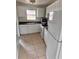 Galley kitchen with white appliances and cabinets with matching tiled flooring at 21077 Gertrude Ave, Port Charlotte, FL 33952