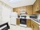 Traditional kitchen features wood cabinets, white appliances, tile floors, and white countertops at 2700 Bayshore Blvd # 3210, Dunedin, FL 34698