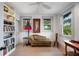 Bright bedroom with a ceiling fan, two windows, hardwood floors, and a cozy chaise lounge at 1007 N Wheeler St, Plant City, FL 33563