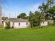 White exterior view of a charming home with green lawn and mature landscaping at 602 E Laura St, Plant City, FL 33563