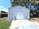 Exterior view of the white storage building with double doors and surrounding greenery at 7943 Woodvine Cir, Tampa, FL 33615