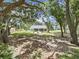 Exterior view through the trees showcasing a well manicured backyard with a screened porch and exterior patio set at 106 Corbett Rd, Lithia, FL 33547