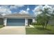 Well-maintained home with a blue garage door, palm trees, and a manicured lawn at 13443 Graham Yarden Dr, Riverview, FL 33579