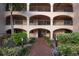 Charming condo entrance with brick path, lush landscaping, and covered walkways to units at 23465 Harborview Rd # 223, Punta Gorda, FL 33980