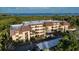 Coastal condo building with balconies, mature landscaping, and covered parking near the water at 23465 Harborview Rd # 223, Punta Gorda, FL 33980