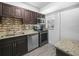 This is a modern kitchen with stainless steel appliances, granite counters, dark wood cabinets, and tile backsplash at 3811 N Oak Dr # E62, Tampa, FL 33611