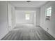 Living room with wood-look flooring, large window, and open doorway at 702 Hillsboro St, Plant City, FL 33563