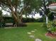 Landscaped backyard with a large tree, stone path, and a wooden bench at 1608 Bob O Link Dr, Venice, FL 34293
