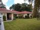 Front view of tan house with red tile roof, landscaping, and a carport at 1608 Bob O Link Dr, Venice, FL 34293