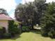 Side yard view with lush landscaping and large tree at 1608 Bob O Link Dr, Venice, FL 34293
