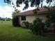 Side view of house showcasing tan exterior, red tile roof, and mature landscaping at 1608 Bob O Link Dr, Venice, FL 34293
