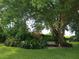 Landscaped backyard with a bench under a large tree at 1608 Bob O Link Dr, Venice, FL 34293