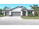 Beautiful two-car garage home featuring gray and white design, complemented by lush green landscaping and paver driveway at 1504 Lugano Cir, Nokomis, FL 34275