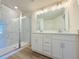 Bathroom with a double sink vanity, large mirror with vanity lighting, and a frameless glass shower at 14016 Emerald Fields Dr, Hudson, FL 34667