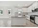 Open kitchen with white cabinets, stainless appliances, granite countertops, island, and tiled floors at 18063 Cherished Loop, Bradenton, FL 34211