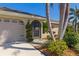 Close-up of the front entrance highlighting lush landscaping, a two-car garage, and an arched front doorway at 1336 Roosevelt Dr, Venice, FL 34293