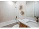 Bright bathroom featuring white marble tile, wood vanity, and bathtub/shower combination at 1741 Lugano Cir, Nokomis, FL 34275