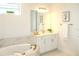 Bright bathroom with a soaking tub, marble countertops, wood flooring, and a large vanity mirror at 229 Vistera Blvd, North Venice, FL 34275