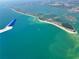 Stunning aerial view of land meeting the ocean, featuring crystal-clear turquoise waters from an airplane window at 468 Ceil Dr, Nokomis, FL 34275