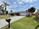 Charming single-story home with a well-manicured lawn, palm trees, and a two-car garage at 468 Ceil Dr, Nokomis, FL 34275