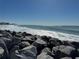 Beautiful ocean view with surfers enjoying the waves, rocky foreground, and buildings visible in the distance at 468 Ceil Dr, Nokomis, FL 34275