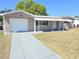 Home exterior featuring an attached garage and a front yard at 4823 Blossom Dr, Holiday, FL 34690