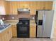 Cozy kitchen with wooden cabinetry, black appliances, and a stainless steel refrigerator at 5014 Galaxy Dr, New Port Richey, FL 34652