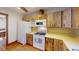 This kitchen features wood cabinets, white appliances, and wood floors at 671 Roanoke Rd, Venice, FL 34293