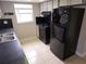 Galley kitchen with white cabinets, black appliances, and tile flooring at 7352 Sequoia Dr, New Port Richey, FL 34653