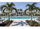 Stunning pool area featuring clear blue water, palm trees, lounge chairs, and a stylish clubhouse in the background at 17982 Cherished Loop, Bradenton, FL 34211