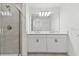 Bathroom featuring a tiled shower, double sinks, white cabinets, and black hardware at 5425 Tripoli Dr, Palmetto, FL 34221