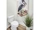 Neutral powder room with a modern toilet and an elegant bird print on the wall at 7959 Chandler Lake Ct, Hudson, FL 34667