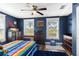 Charming bedroom with two large windows, hardwood floors, ceiling fan, and vibrant blue accent wall at 3703 Cooper Rd, Plant City, FL 33565