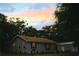 Exterior view of a home at dusk under a colorful sky and shady trees at 3703 Cooper Rd, Plant City, FL 33565