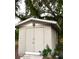 Exterior view of a gray shed with double doors, lighting, and brick on one side at 3703 Cooper Rd, Plant City, FL 33565