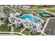 Aerial view of a modern clubhouse featuring a large pool, palm trees, ample seating, and manicured landscaping at 17212 Savory Mist Cir, Lakewood Ranch, FL 34211