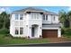 New construction features a white two-story home with a gray roof, lush landscaping, and a two-car garage at 17212 Savory Mist Cir, Lakewood Ranch, FL 34211