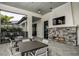 Relax on the outdoor patio with a stone fireplace, TV, and dining tables at 17212 Savory Mist Cir, Lakewood Ranch, FL 34211