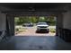 View from inside a two-car garage with an open garage door showing brick pavers and two parked cars at 2735 Lavandula Ct, North Port, FL 34289