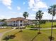 An aerial view of the clubhouse showcasing an elegant exterior, lush landscaping, and a golf course at 5599 Hidden Oak Ct, North Port, FL 34287
