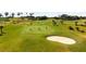 Scenic golf course with manicured greens, a sand trap, and golfers on a bright, sunny day at 5599 Hidden Oak Ct, North Port, FL 34287