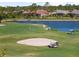 Picturesque golf course view with a pond, sand trap, and golfers enjoying a sunny day on the green at 5599 Hidden Oak Ct, North Port, FL 34287